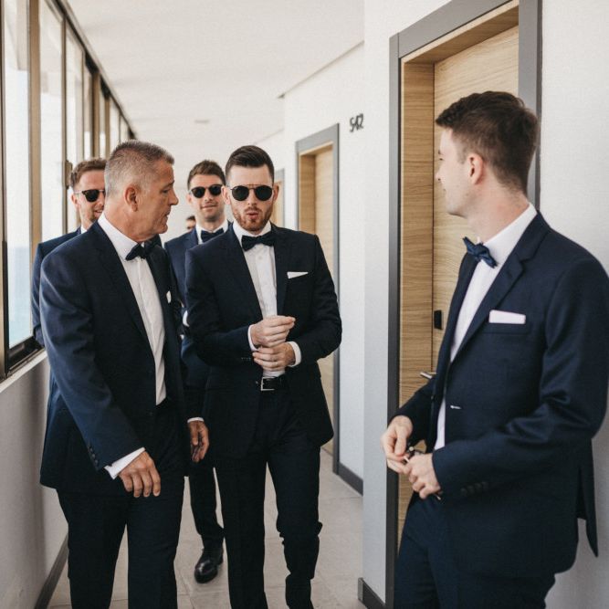 Stylish Groomsmen in Navy Suits with Bow Ties and Sunglasses