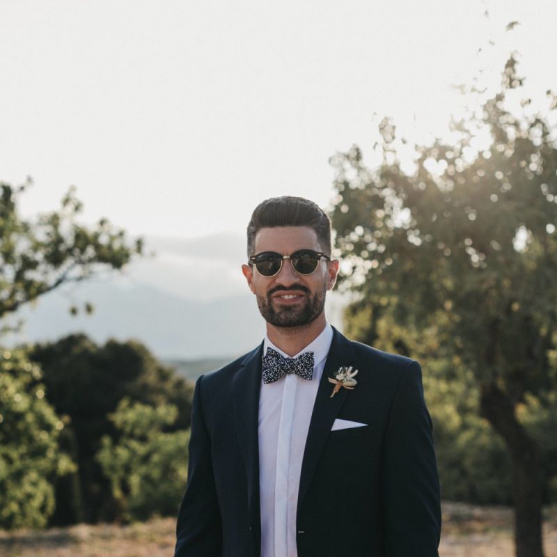 Stylish Groom in Navy Suit with Floral Bow Tie and Sunglasses