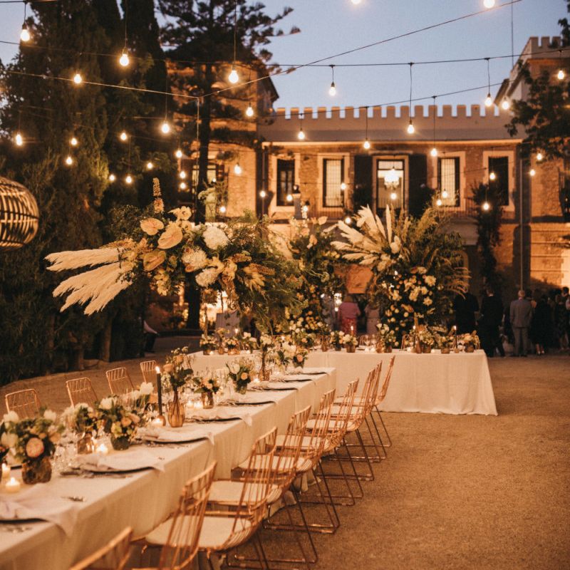 Outdoor Spanish Wedding Reception with Festoon Lights and Flower Installation