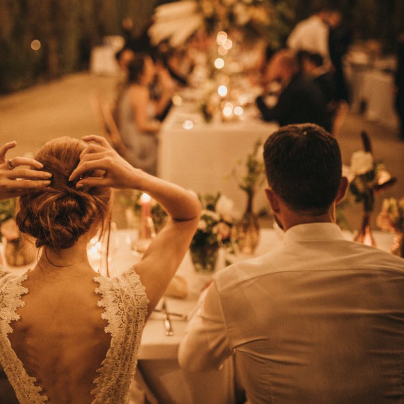 Bride in Lace Low Back Wedding Dress Sitting at the Top Table