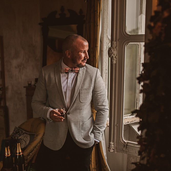 Groom in Beige Blazer and Bow Tie Looking Out the Window