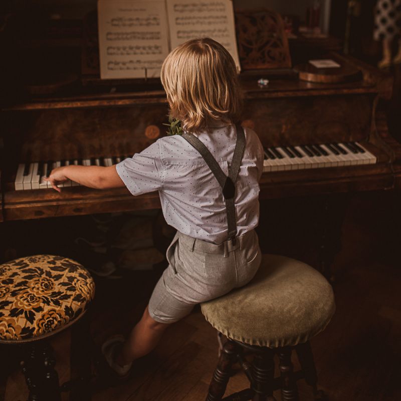 Young Boy in Shorts and Blazer Sitting at a Piano