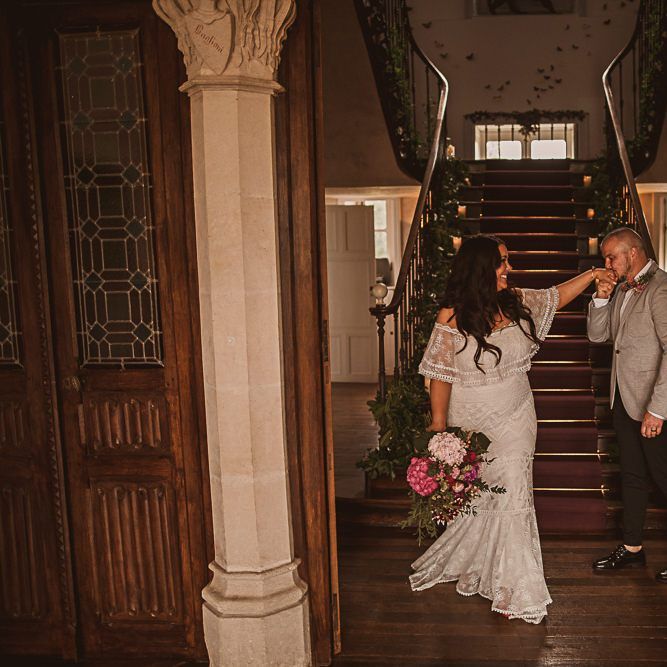Groom in Grey Blazer and Bow Tie Kissing His Brides Hand in aGrace Loves Lace Wedding Dress