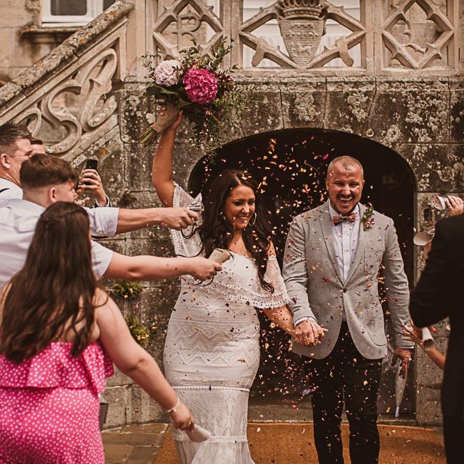 Confetti Moment with Bride in Grace Loves Lace Wedding Dress and Groom in Grey Blazer and Bow Time
