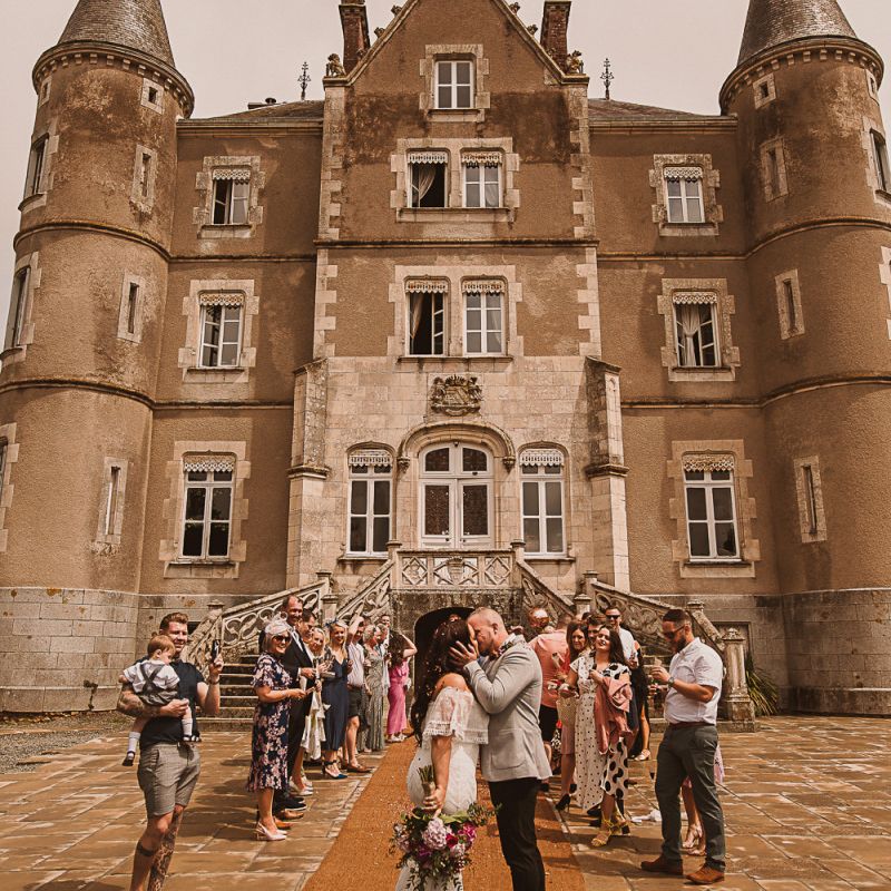 Bride in Grace Loves Lace Wedding Dress and Groom in Grey Blazer and Bow Time Kissing in Front of the French Chateau featured on escape to the chateau