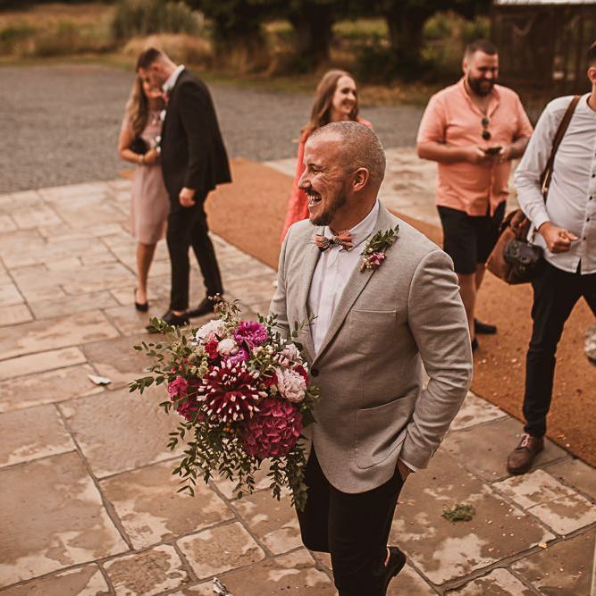 Groom in Grey Blazer and Bow Tie Holding a Pink Wedding Bouquet featured on escape to the chateau