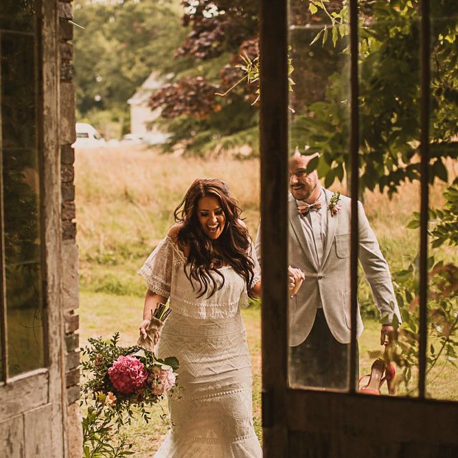Bride in Emanuela Grace Loves Lace Wedding Dress and Groom in Grey Blazer Walking into the French Chateau Wedding Reception