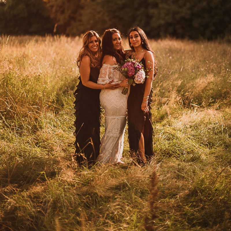 Bridal Party Portrait with Bride in Emanuela Grace Loves Lace Wedding Dress and Bridesmaids in Black Dresses