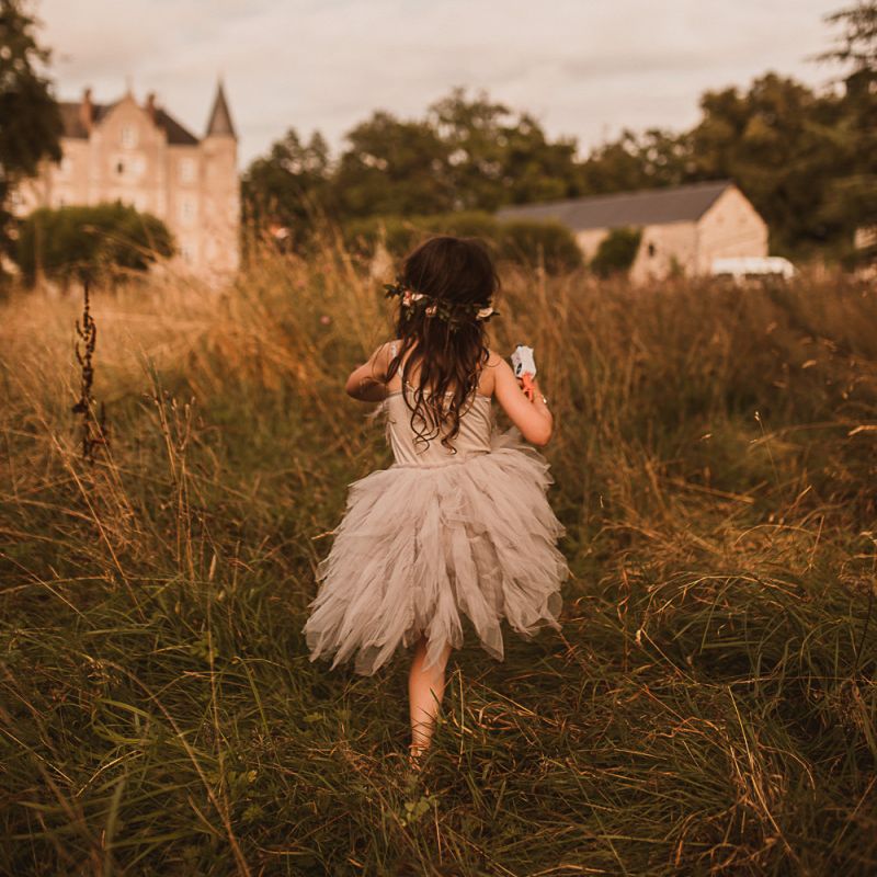 Flower Girl in Grey Tulle Tutu Running Through a Field
