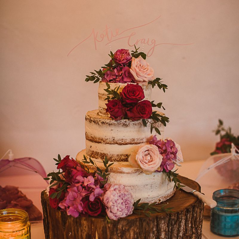 Semi Naked Wedding Cake Decorated with Pink Flowers on a Rustic Tree Slice Cake Stand escape to the chateau