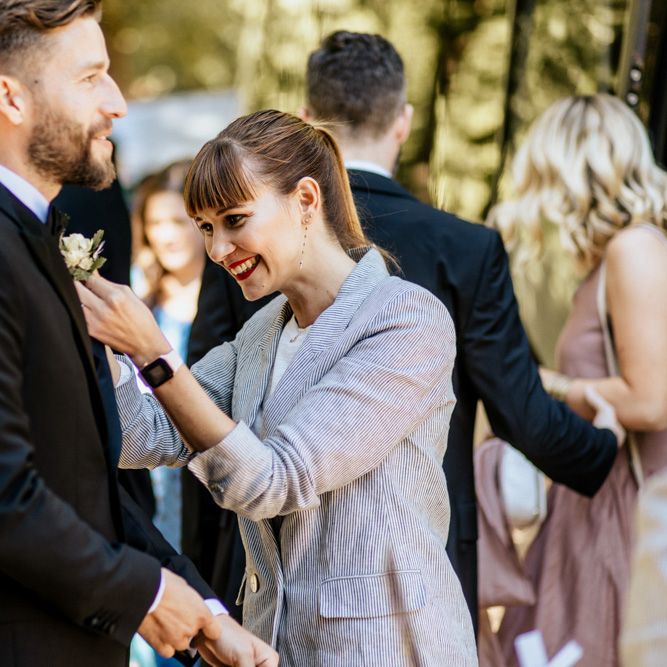 Groom in Givenchy Black Tuxedo Having His Buttonhole Put On