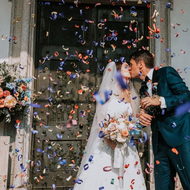 Confetti exit for bride and groom with bride carrying  pastel bouquet
