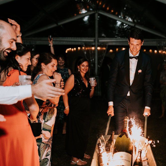 Groom wheels in champagne bottles with sparklers
