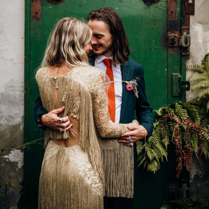 Bride in Gold Fringe Dress with Groom in Navy Suit with Orange Tie and Floral Buttonhole