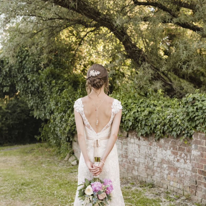 Bride in Lacy Fishtail Stella York Gown with Plunging V Back and Diamante Charm on Champagne Ribbon Belt | Summer Bridal Bouquet with Purple and Blue Flowers and Eucalyptus | Back Necklace by Chez Bec | Morris Minor Wedding Car, Hanging Flowers in Bottles and Town Crier for Village Hall Wedding in Rye | Eleanor Jane Photography