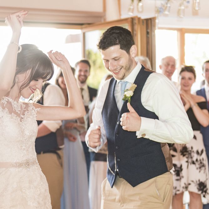 Bride in Lacy Fishtail Stella York Gown with Plunging V Back and Diamante Charm on Champagne Ribbon Belt | Groom in Blue Jacket and Waistcoat with Camel Chinos | Wedding Reception at Udimore Village Hall, East Sussex | Morris Minor Wedding Car, Hanging Flowers in Bottles and Town Crier for Village Hall Wedding in Rye | Eleanor Jane Photography