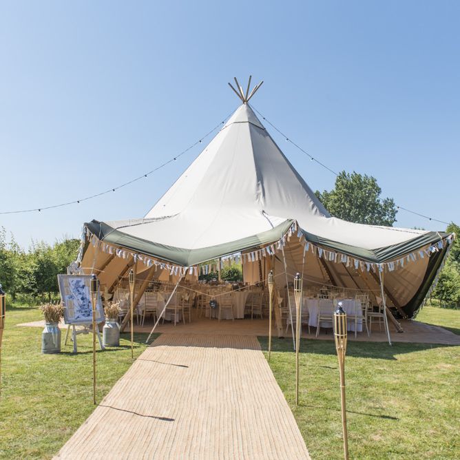 Tipi Wedding Reception at Udimore Village Hall, East Sussex | Wood Sign | Hessian Carpet | Wooden Stakes | Festoon Lights | Milk Churns | Pastel Bunting | Morris Minor Wedding Car, Hanging Flowers in Bottles and Town Crier for Village Hall Wedding in Rye | Eleanor Jane Photography