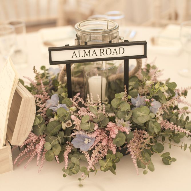 Flower Garland Centrepieces | Pillar Candle | Wedding Advice Cards | Road Sign Table Names | Tipi Wedding Reception at Udimore Village Hall, East Sussex | Morris Minor Wedding Car, Hanging Flowers in Bottles and Town Crier for Village Hall Wedding in Rye | Eleanor Jane Photography
