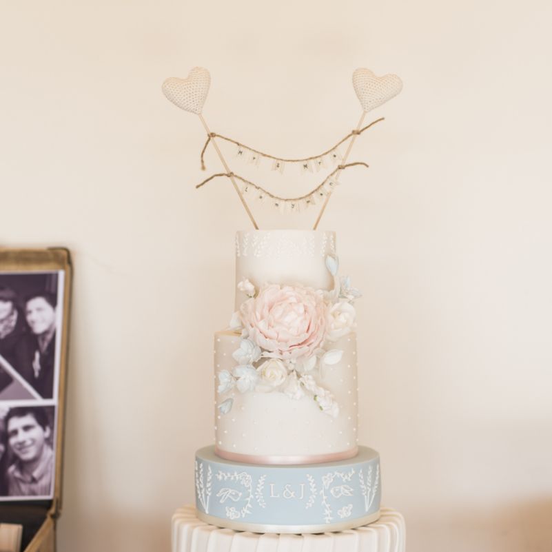 Four Tier Wedding Cake with Decorative Fondant Icing and Pink Fondant Flower | Mr and Mrs Cake Topper with Heart Sticks and Twine | Morris Minor Wedding Car, Hanging Flowers in Bottles and Town Crier for Village Hall Wedding in Rye | Eleanor Jane Photography