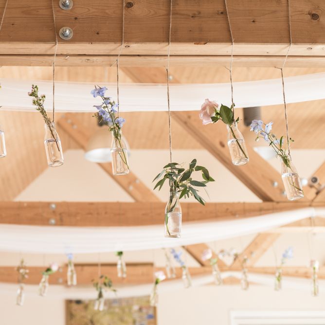 Flowers in Milk Bottles Hanging from Beams | Morris Minor Wedding Car, Hanging Flowers in Bottles and Town Crier for Village Hall Wedding in Rye | Eleanor Jane Photography