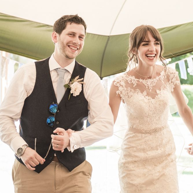 Bride in Lacy Fishtail Stella York Gown with Plunging V Back and Diamante Charm on Champagne Ribbon Belt | Groom in Blue Jacket and Waistcoat with Camel Chinos | Tipi Wedding Reception at Udimore Village Hall, East Sussex | Morris Minor Wedding Car, Hanging Flowers in Bottles and Town Crier for Village Hall Wedding in Rye | Eleanor Jane Photography