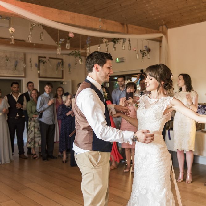 Bride in Lacy Fishtail Stella York Gown with Plunging V Back and Diamante Charm on Champagne Ribbon Belt | Groom in Blue Jacket and Waistcoat with Camel Chinos | Flowers in Milk Bottles Hanging from Beams | Wedding Reception at Udimore Village Hall, East Sussex | Morris Minor Wedding Car, Hanging Flowers in Bottles and Town Crier for Village Hall Wedding in Rye | Eleanor Jane Photography