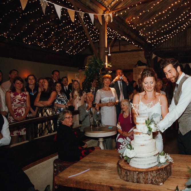 Cutting The Cake // Glastonbury Themed Table Plan For Wedding At Stone Barn Cotwolds With Groom In Cad &amp; The Dandy Images Meghan Lorna
