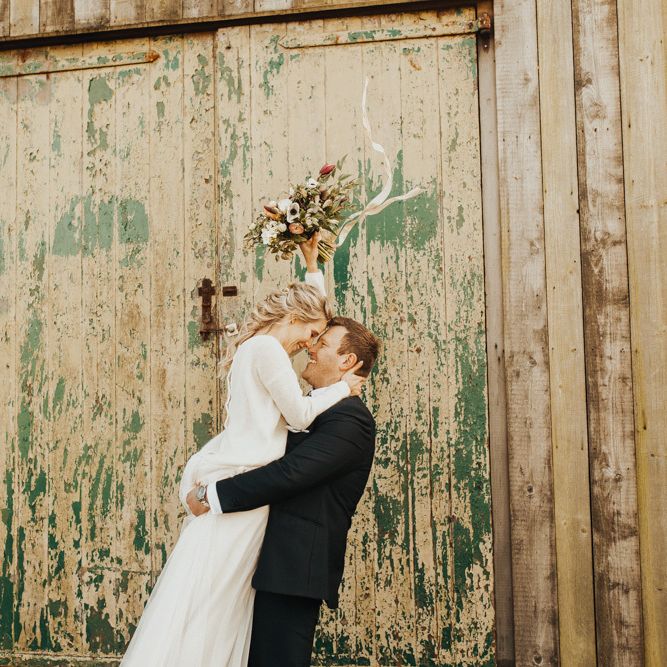 Groom picks up new wife wearing bridal jumper