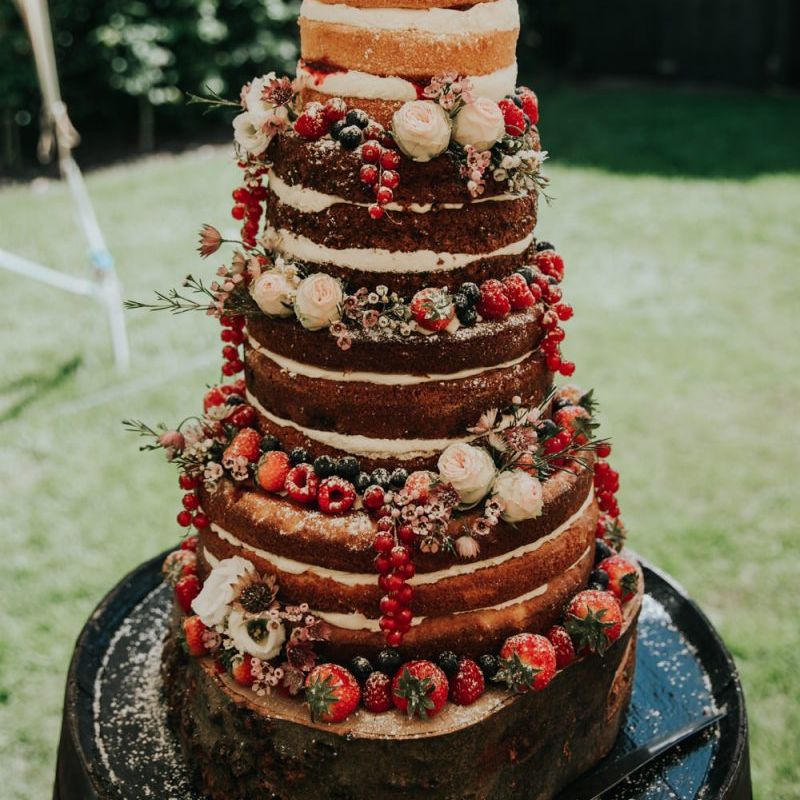 Naked wedding cake with berries and cake topper