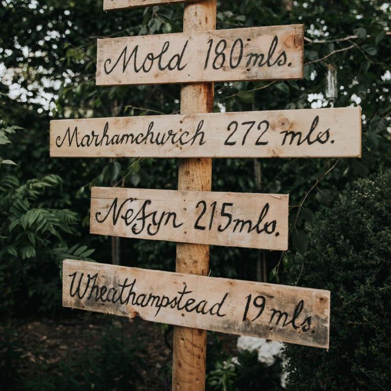 Wooden wedding sign at celebration with different bridesmaid dresses