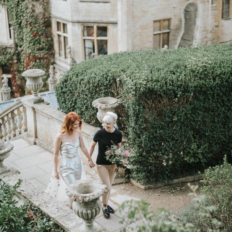 Two brides holding hands walking up the steps