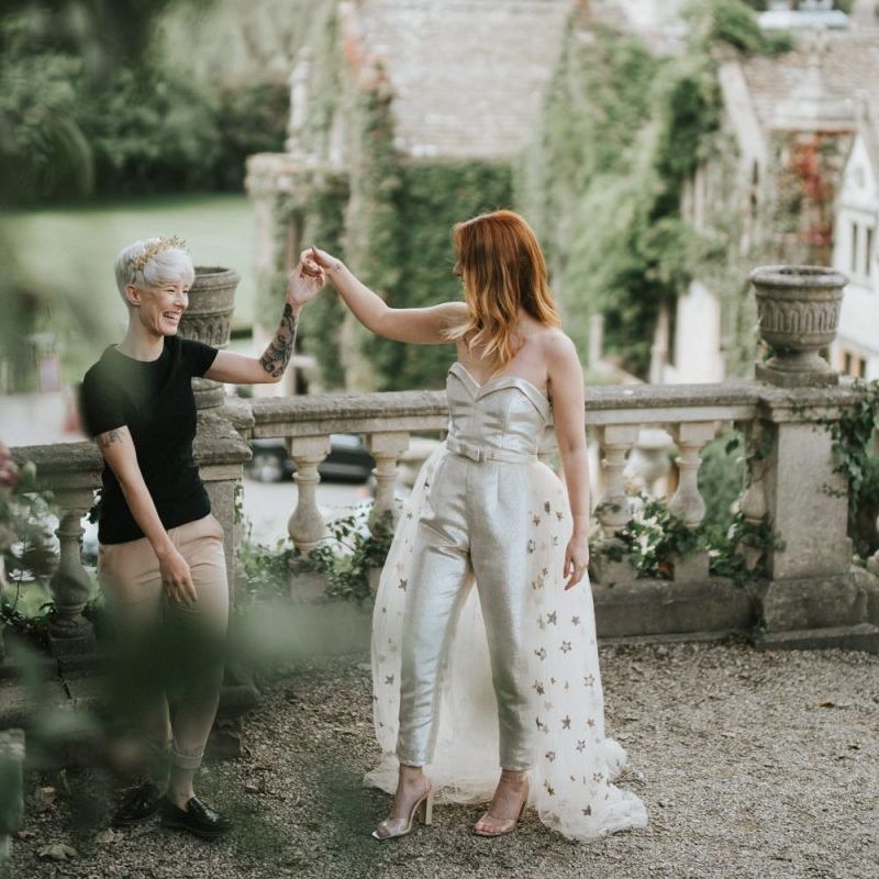 Two brides dancing on the grounds of Castle Combe Manor House in Wiltshire