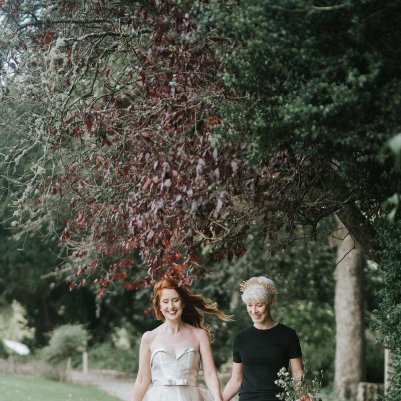 Same sex wedding couple walking through the grounds at Castle Combe Manor House in Wiltshire