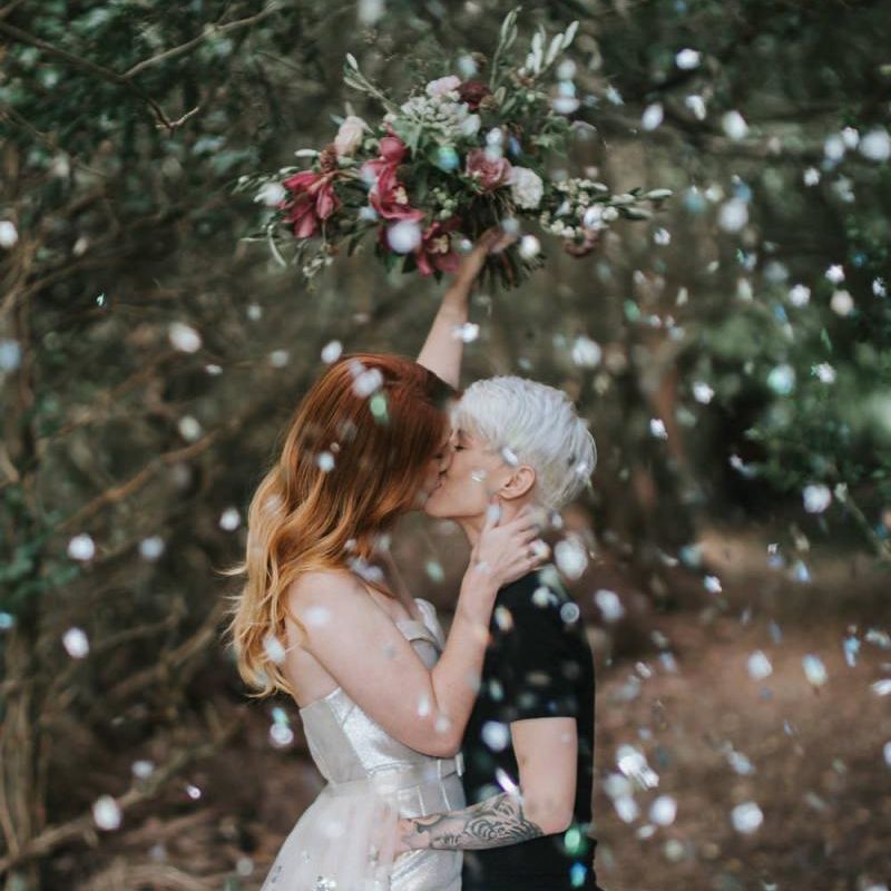 Brides kissing during confetti moment