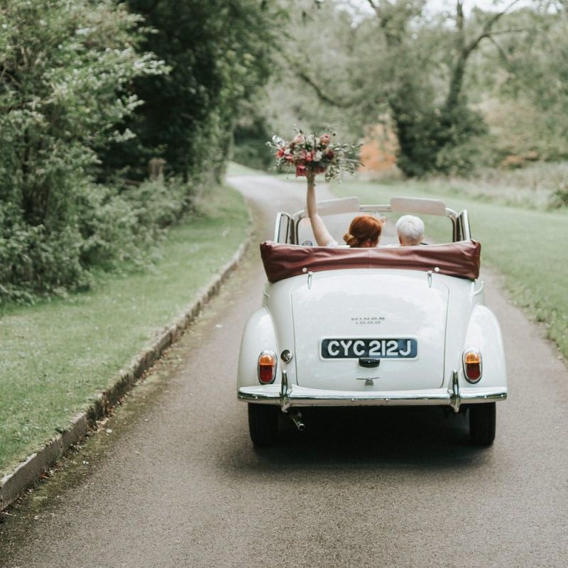 Brides riding off into the sunset in a convertible wedding car