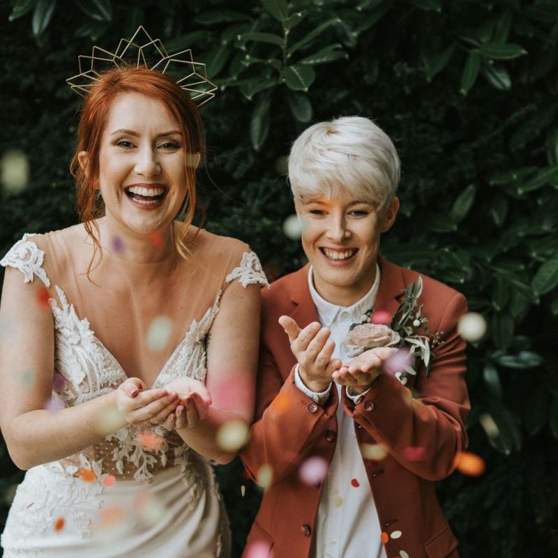 Two brides blowing confetti out of their hands