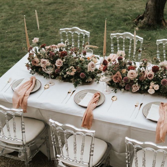 Intimate tablescape with floral centrepiece taper candles and ghost chairs