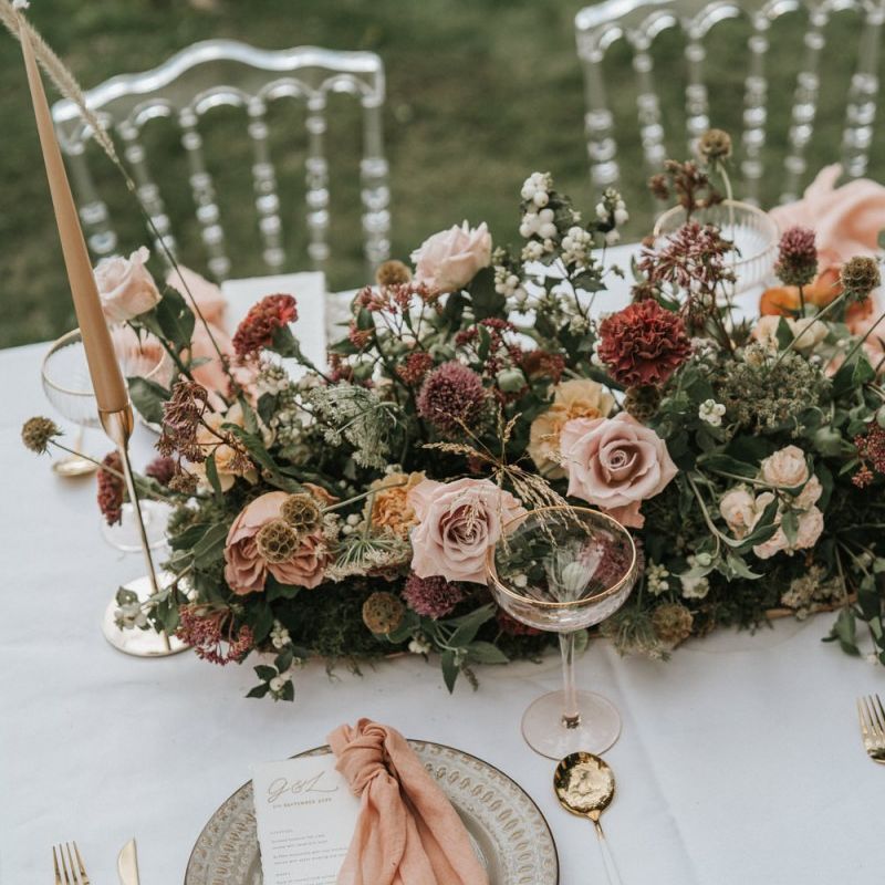 Wedding table decor with floral centrepiece, taper candles and gold cutlery
