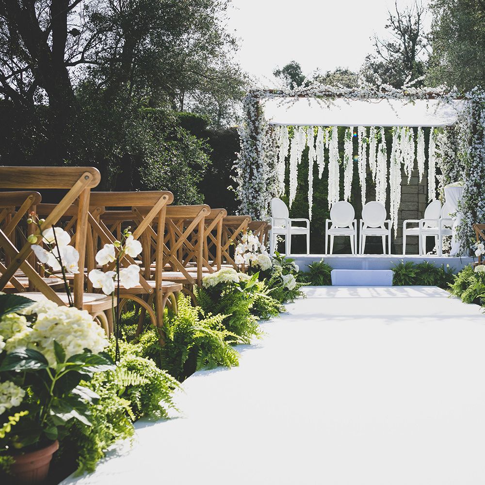 Outdoor wedding decor with flowers and foliage lining the aisle