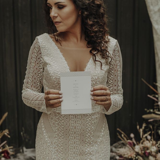 Bride in Boho Lace Wedding Dress Holding Menu Card