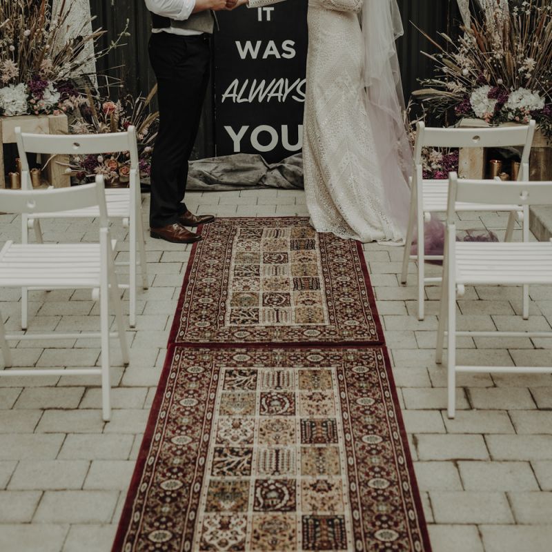 Boho Bride and Groom Standing at the Altar with Woven Rug, Bold Sign and Dried Flower Arrangements