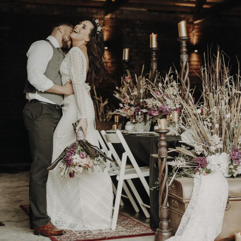 Boho Bride and Groom Standing Next to Tablescape and Dried Flower Arrangements