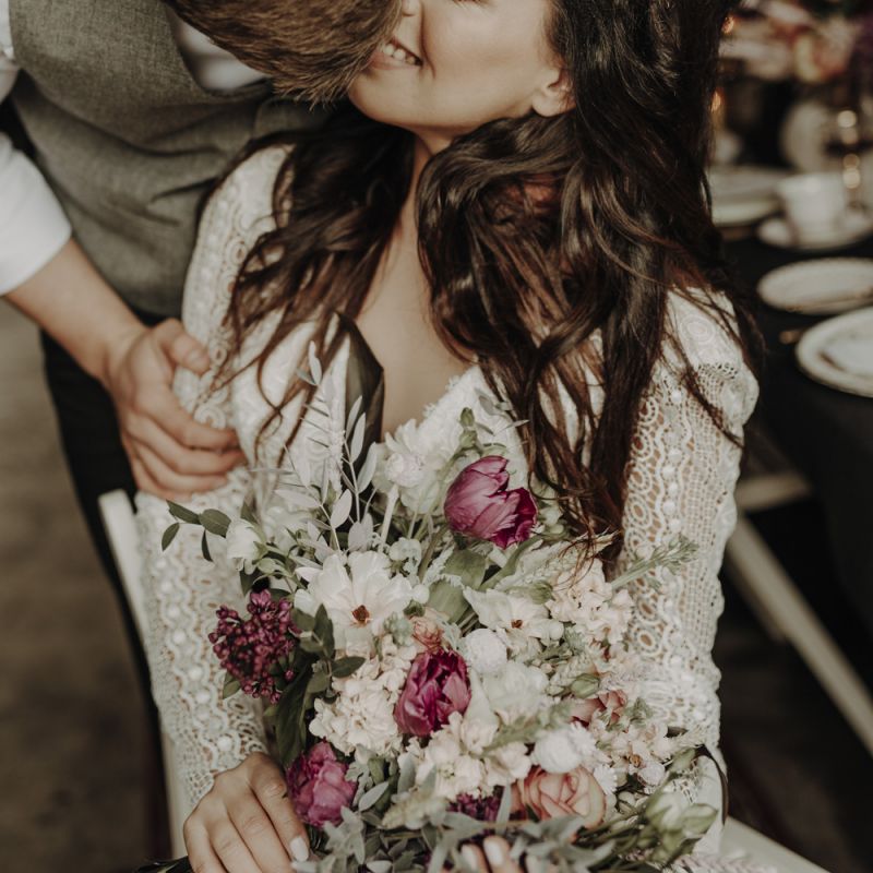 Groom in Wool Waistcoat Kissing Bride in Lace Wedding Dress