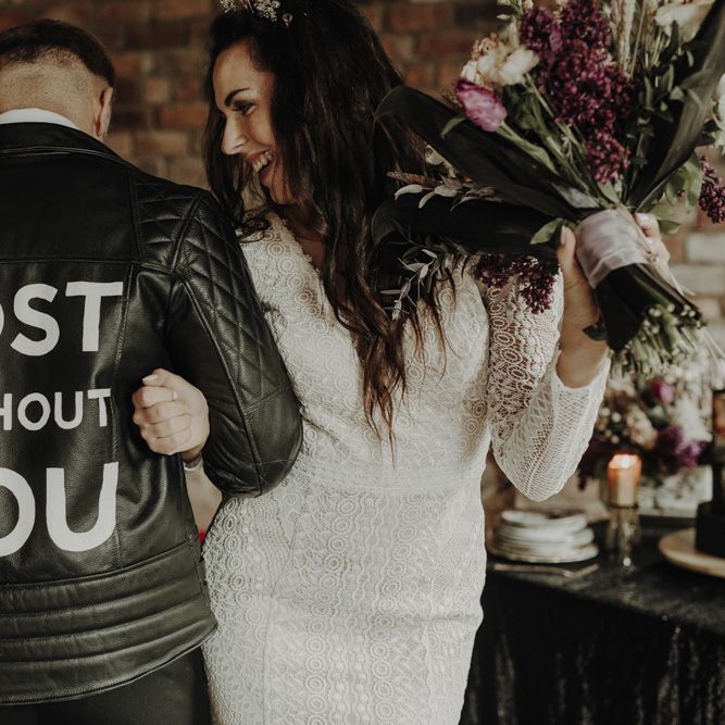 Groom in Personalised Leather Jacket  Linking Arms with Bride in Lace Wedding Dress