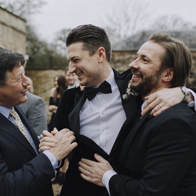 Groom in Black Tie Suit Being Congratulated by His Friends