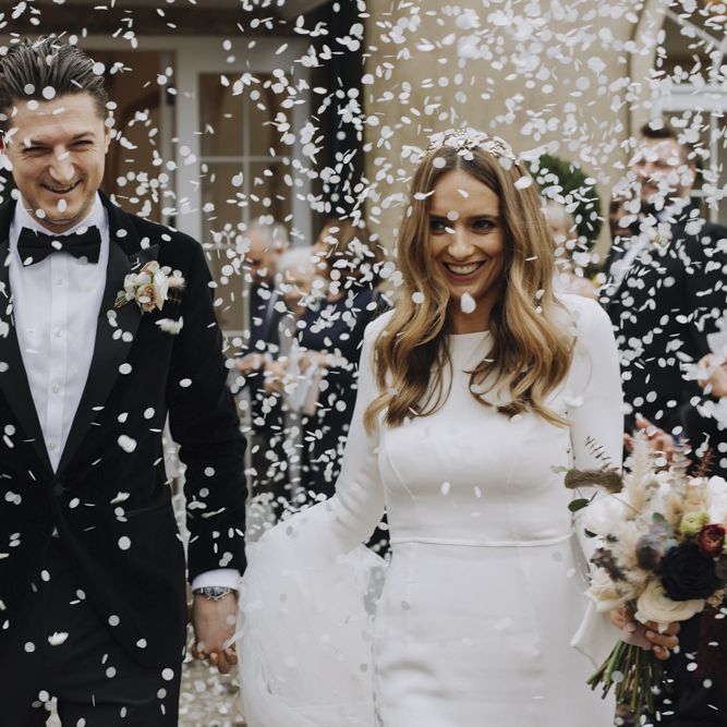 White Confetti Bomb Moment with Bride in Emma Beaumont Wedding Dress and Groom in Tuxedo