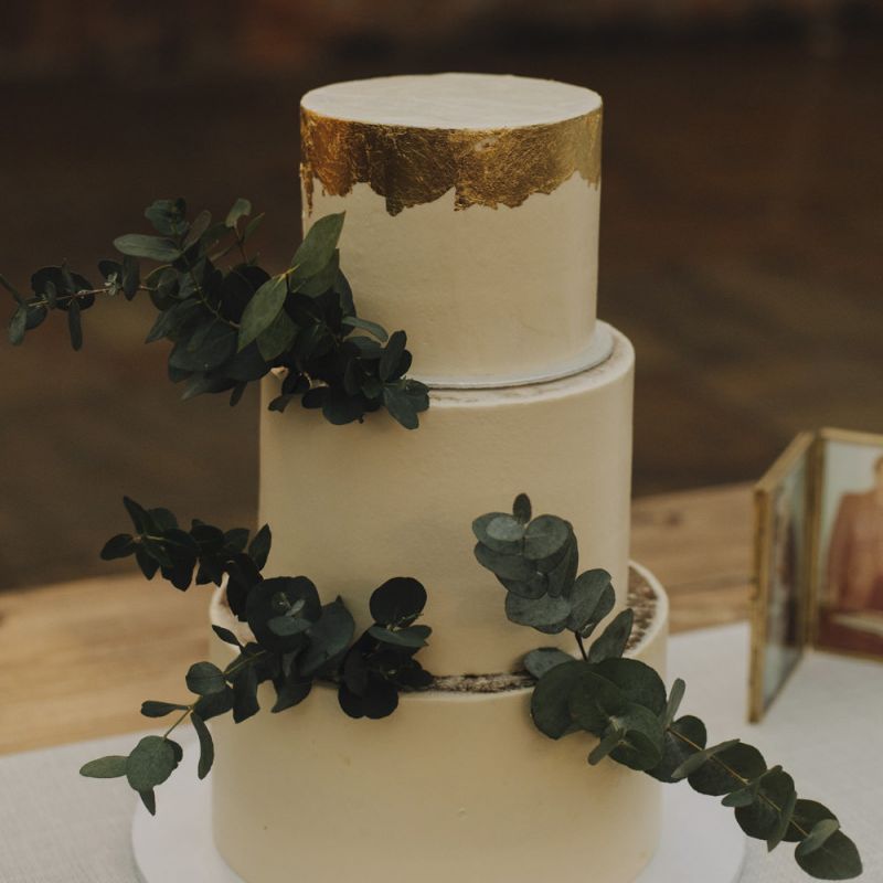 White Wedding Cake with Gold Leaf Detailing and Eucalyptus Decor