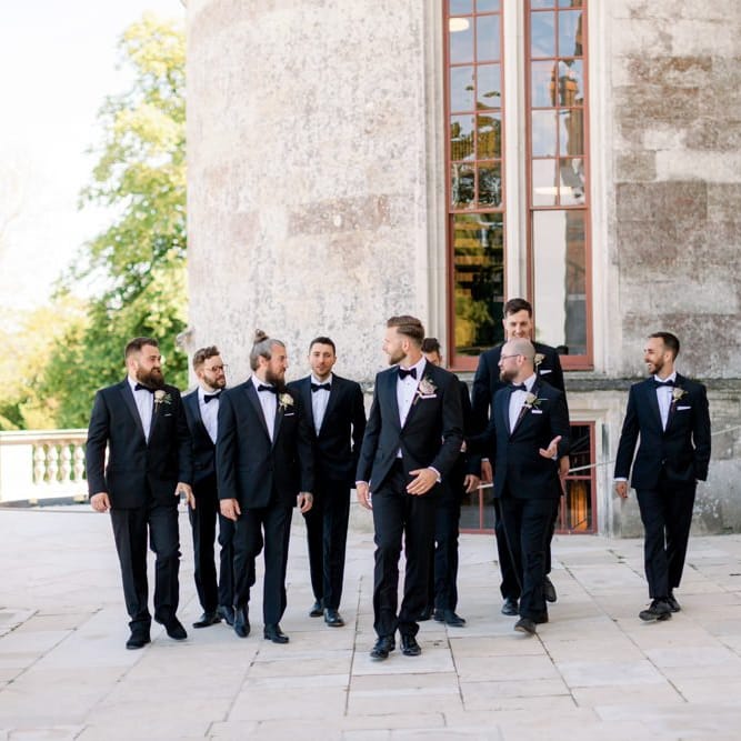 Groom with groomsmen in matching black tuxedo wedding suits