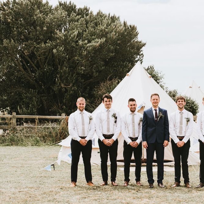Groom and groomsmen in matching outfits for festival themed wedding