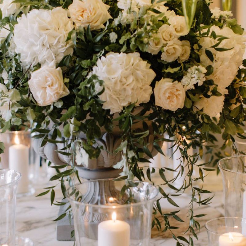 White wedding flowers and candles in hurricane vases